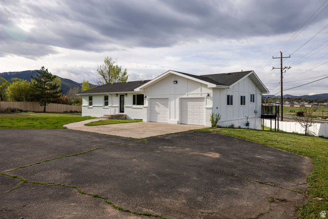 4155 Johnson Road Nibley, UT 84321 - Photo 54 of 71 View of front of home with board and batten siding, a shingled roof, driveway, a garage, and a mountain view