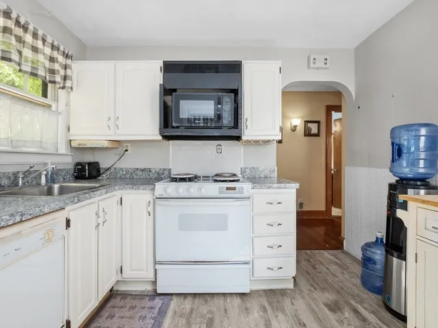 a kitchen with granite countertop white cabinets and white appliances