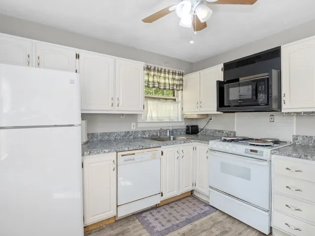 a kitchen with granite countertop white cabinets white stainless steel appliances and sink