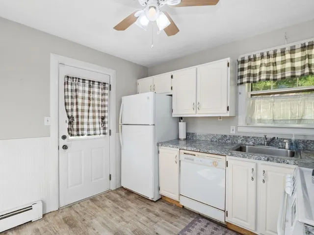a kitchen with a refrigerator a stove cabinets and wooden floor