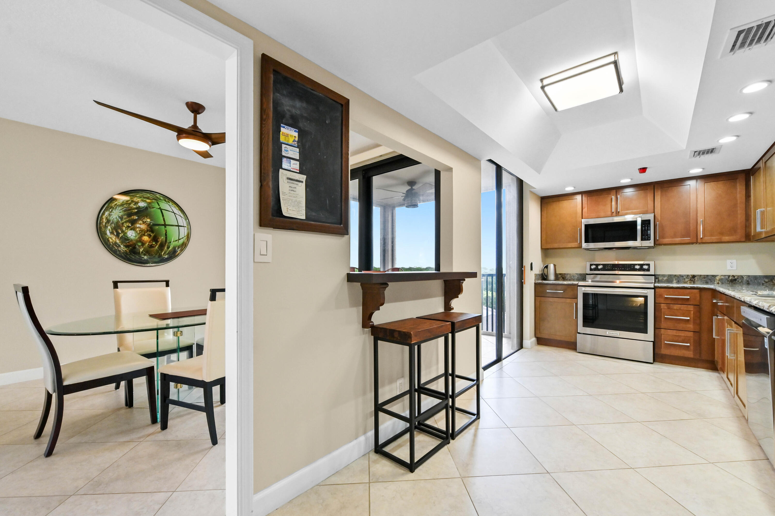5951 Wellesley Park Drive, Unit 702 Boca Raton, FL 33433 - Photo 1 of 26 a kitchen with stainless steel appliances a stove a refrigerator cabinets and a dining table