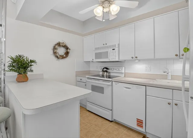 a kitchen with white cabinets and white appliances