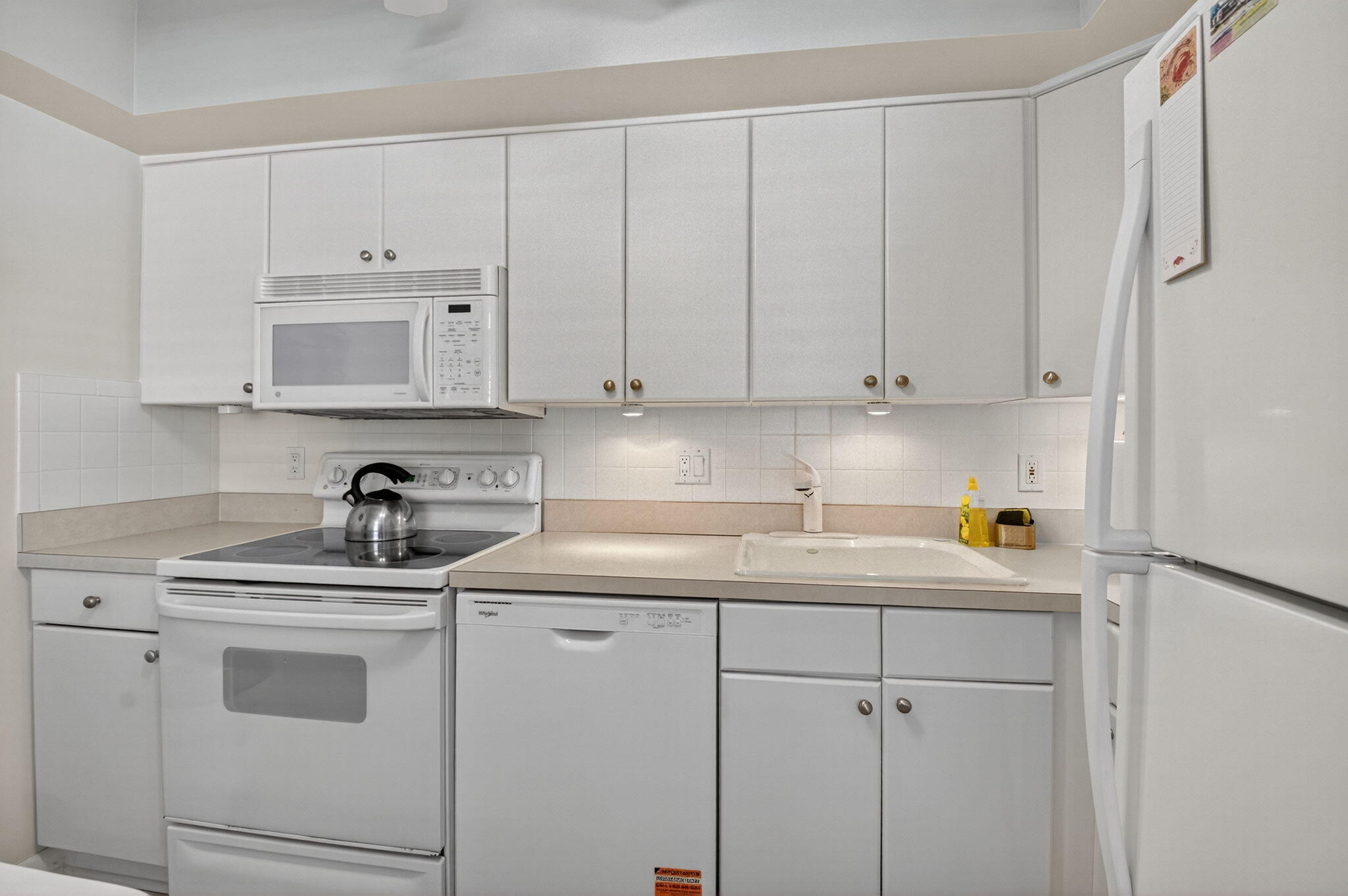 5505 North Ocean Boulevard, Unit 8204 Ocean Ridge, FL 33435 - Photo 13 of 47 a kitchen with white cabinets and white appliances