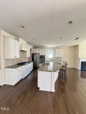 a large white kitchen with lots of counter top space and living room