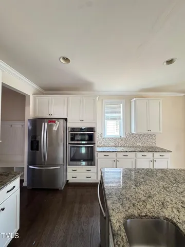 a kitchen with granite countertop a refrigerator and a sink