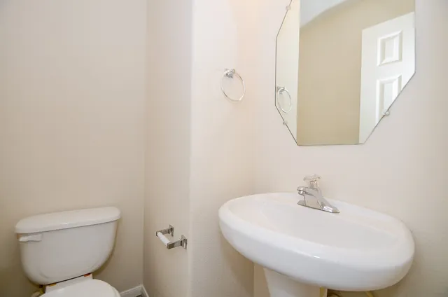 a bathroom with a toilet a sink and mirror