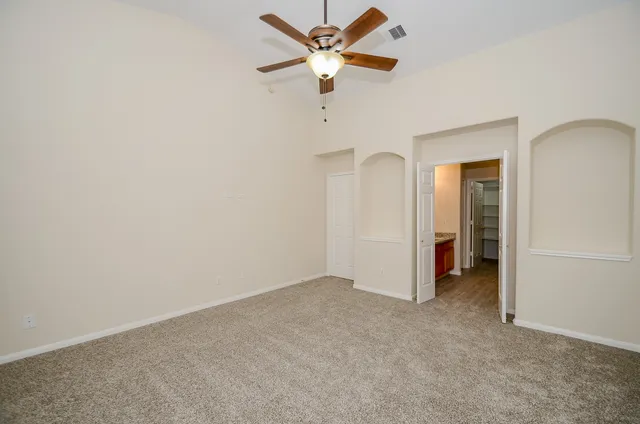 an empty room with closet and a ceiling fan