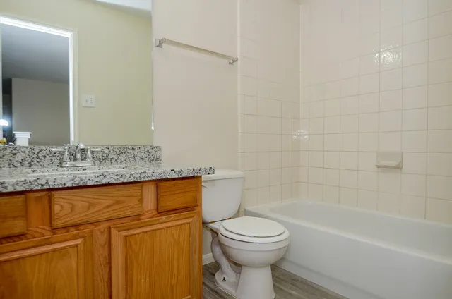 a bathroom with a granite countertop bathtub toilet and sink