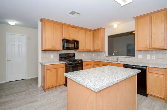 a kitchen with stainless steel appliances granite countertop a sink stove microwave and refrigerator