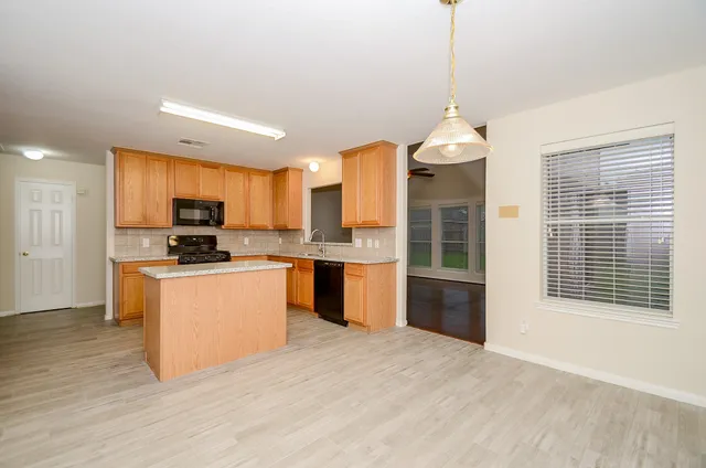 a kitchen with granite countertop wooden floors stainless steel appliances a sink