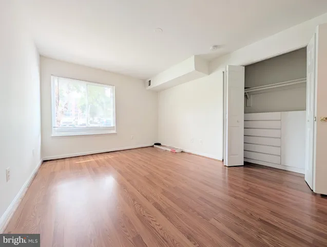 an empty room with wooden floor closet and windows
