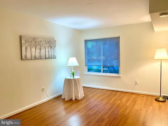 a view of an empty room with window and wooden floor