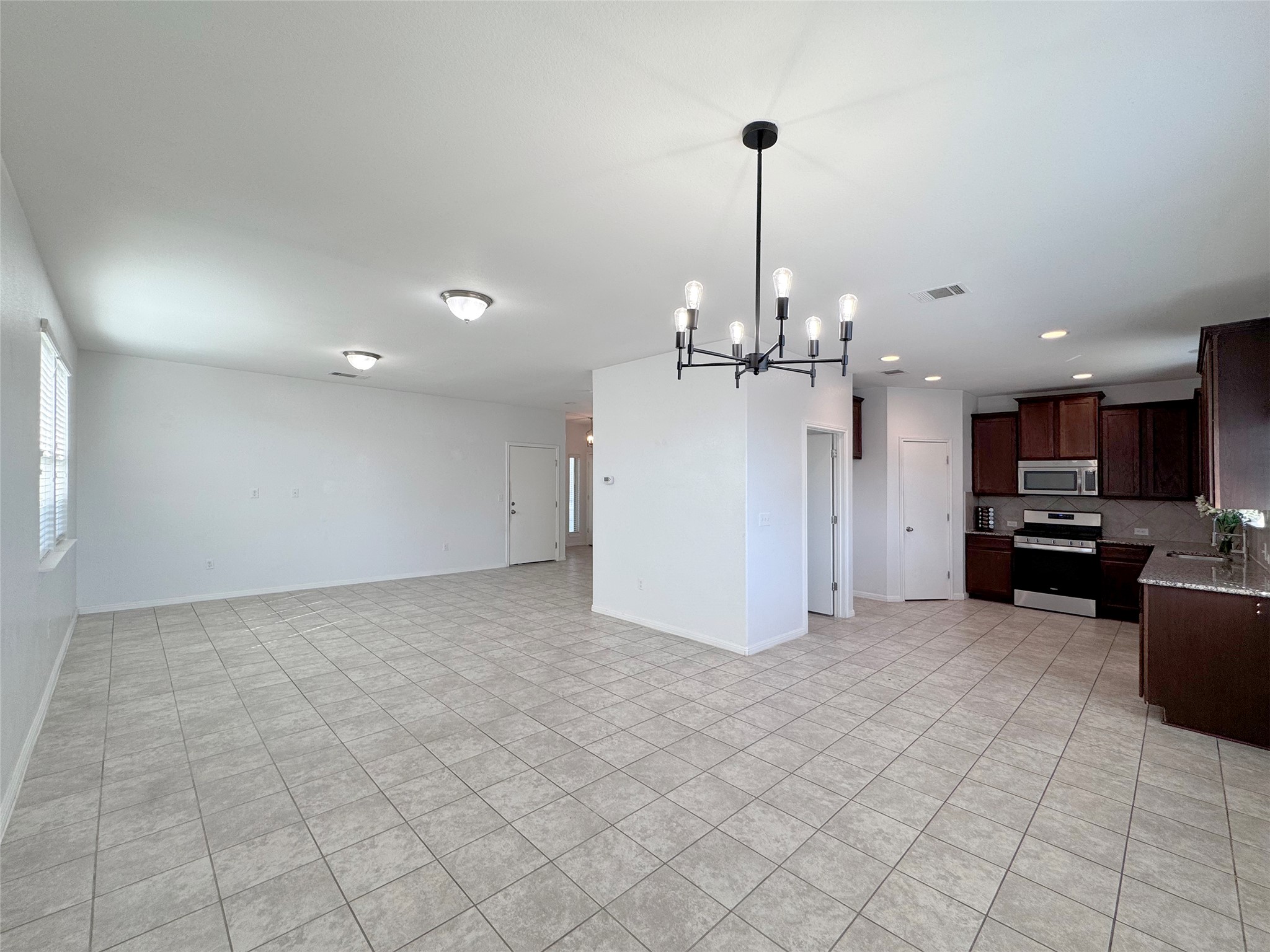 251 Triumph Road Buda, TX 78610 - Photo 26 of 26 Kitchen featuring stainless steel appliances, dark wood finish cabinetry, open floor plan, hanging lights, and light tile patterned floors