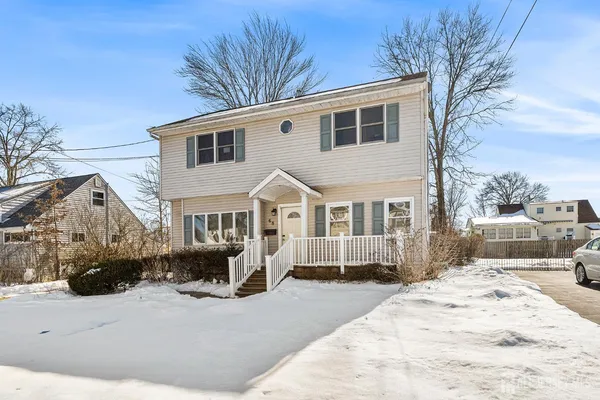 a front view of a house with a yard covered in snow