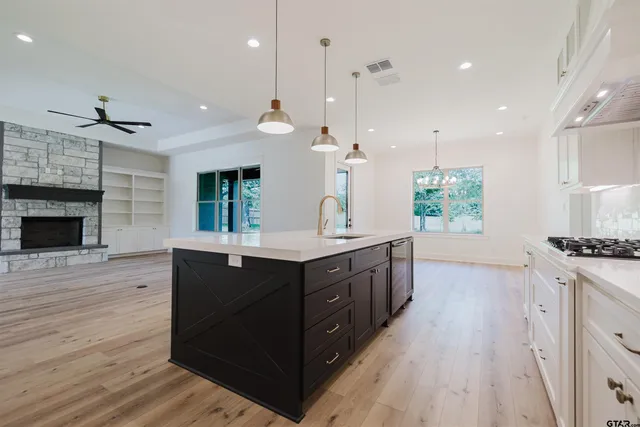 a kitchen with stainless steel appliances granite countertop a sink a stove and a wooden floors