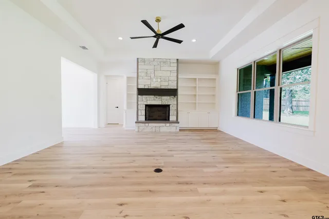 a view of an empty room with a ceiling fan and window