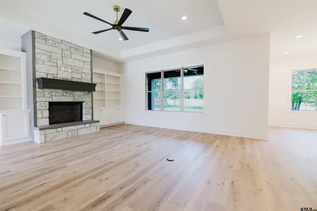 an empty room with wooden floor a ceiling fan and a fireplace
