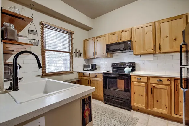 a kitchen with granite countertop a sink a stove and cabinets