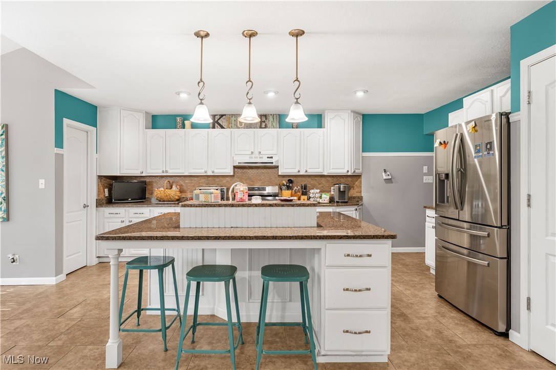155 Ridgewood Boulevard Belpre, OH 45714 - Photo 20 of 49 Kitchen with backsplash, a kitchen breakfast bar, stainless steel appliances, hanging light fixtures, and a kitchen island