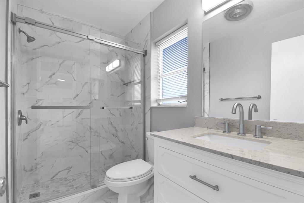 4751 Northeast 21st Terrace, Unit 4 Lighthouse Point, FL 33064 - Photo 13 of 22 a bathroom with a granite countertop sink toilet and shower