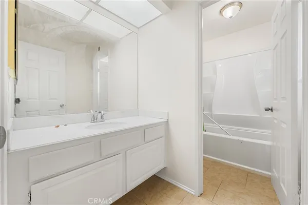 a bathroom with a tub sink double vanity and mirror