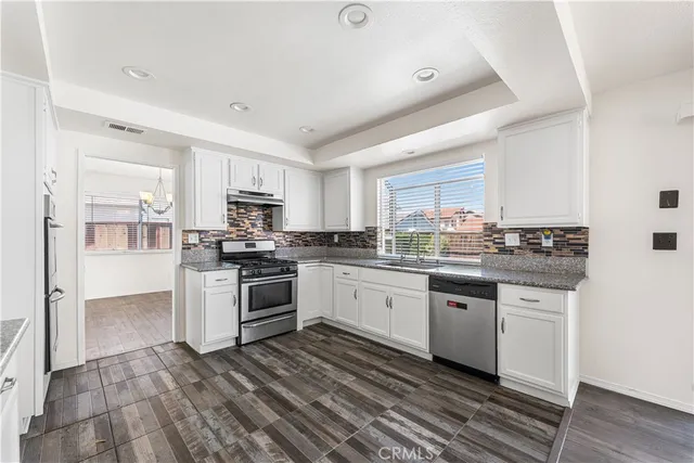 a kitchen with granite countertop a stove top oven and cabinets
