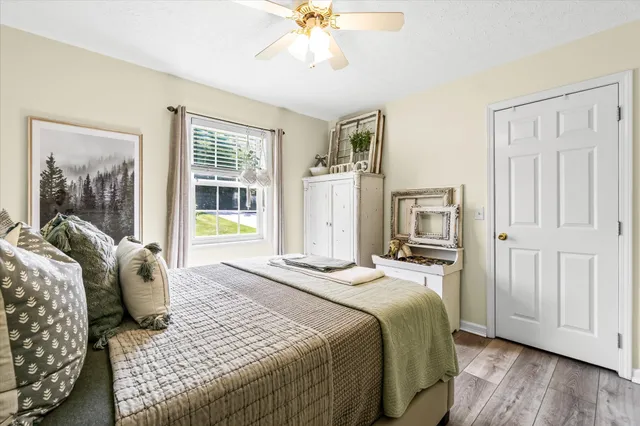 a bedroom with a bed painting on wall and a large window