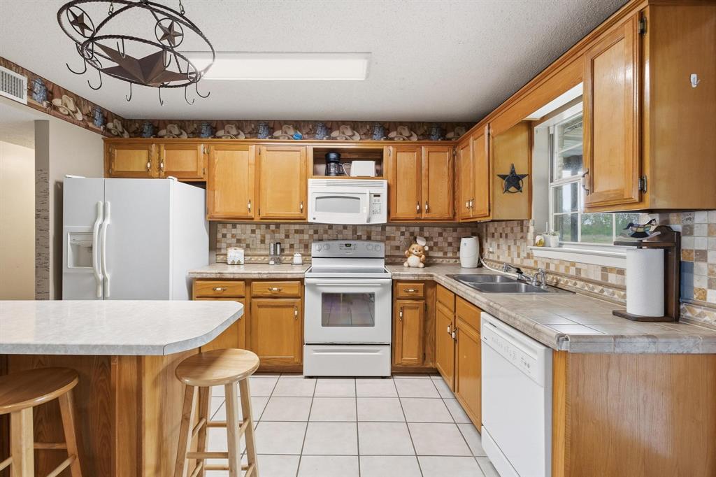 472 Milton-Minter Road Deport, TX 75435 - Photo 11 of 30 a kitchen with stainless steel appliances kitchen island granite countertop a sink a stove a refrigerator a washer dryer and a dining table