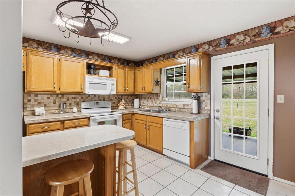 472 Milton-Minter Road Deport, TX 75435 - Photo 13 of 30 a kitchen with stainless steel appliances granite countertop a stove a sink dishwasher and a microwave oven with cabinets