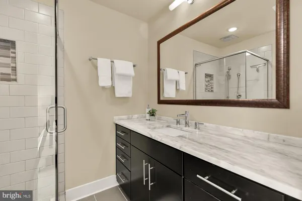 a bathroom with a granite countertop sink a mirror and a shower