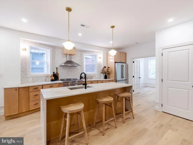 a kitchen with kitchen island a dining table chairs sink and cabinets
