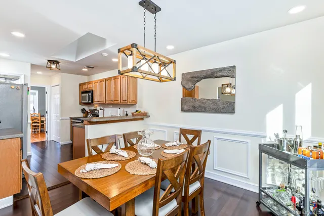 a dining room with wooden floor a chandelier a glass table and chairs