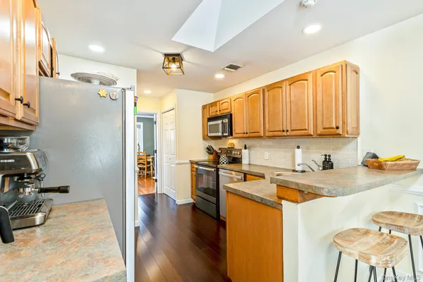 a kitchen with stainless steel appliances granite countertop a refrigerator a stove and a sink with wooden floor