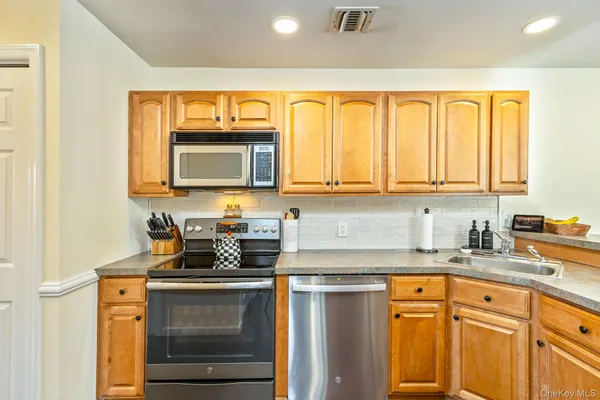 a view of a kitchen with stainless steel appliances granite countertop a refrigerator a sink and wooden cabinets