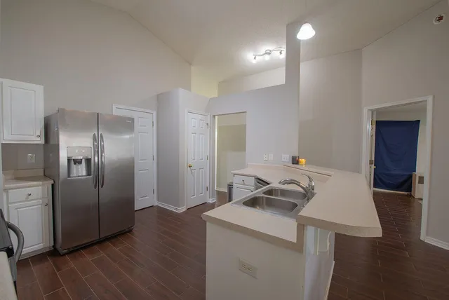 a view of a kitchen with refrigerator and wooden floor