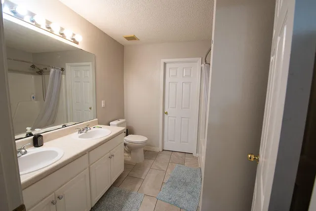 a bathroom with a double vanity sink and mirror with toilet