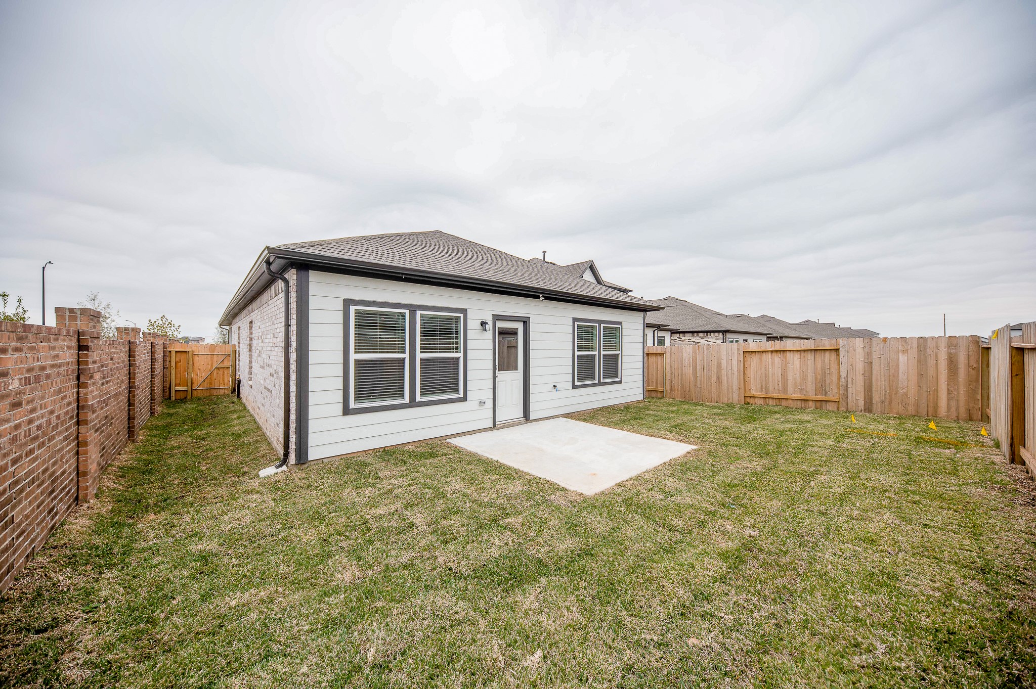 23302 Spring Genesis Lane Katy, TX 77493 - Photo 32 of 32 This photo shows a cozy backyard with a small patio area, surrounded by wooden fencing. The home features light-colored siding and multiple windows, offering a private outdoor space ideal for relaxing or entertaining.