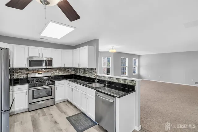 a kitchen with stainless steel appliances granite countertop a stove a sink and a microwave