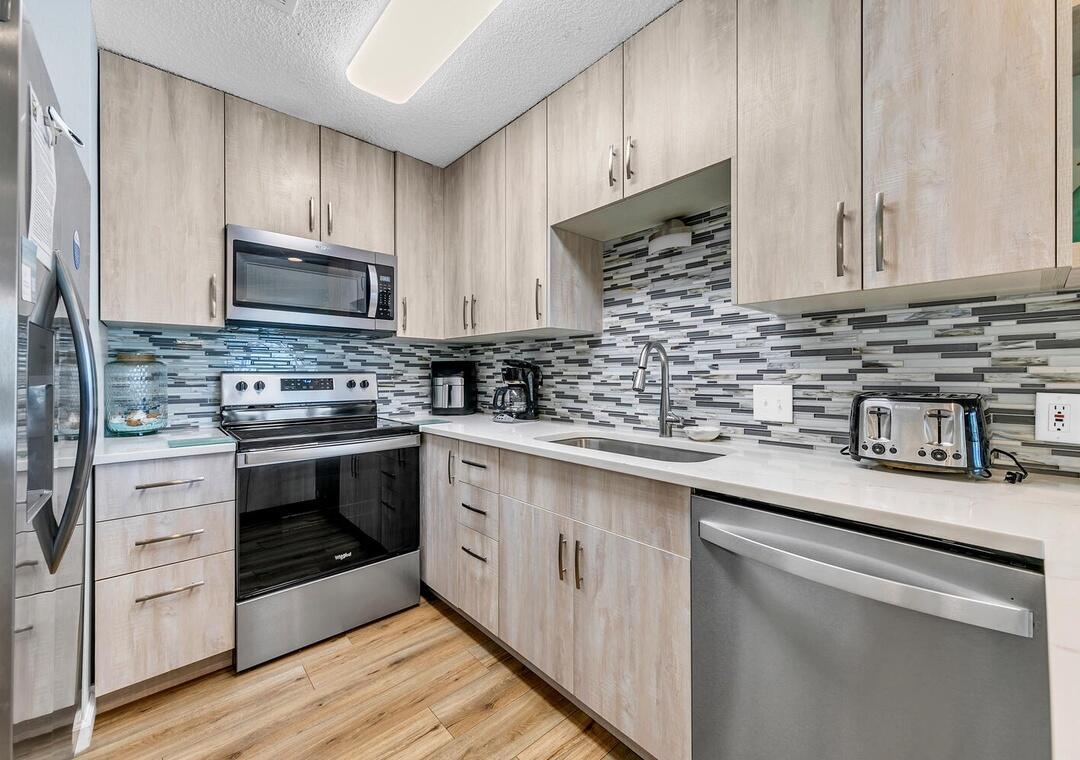 11 Beachside Drive, Unit 832 Santa Rosa Beach, FL 32459 - Photo 9 of 23 a kitchen with stainless steel appliances granite countertop a stove a sink dishwasher and a microwave oven with wooden cabinets