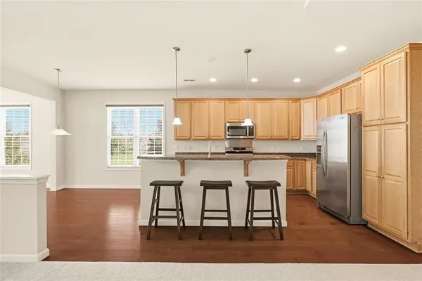 a kitchen with kitchen island granite countertop wooden floors and white cabinets