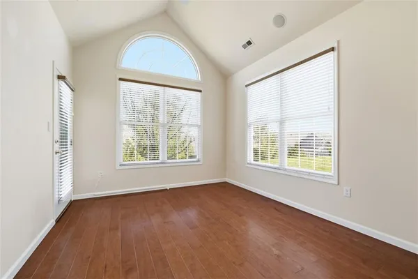 a view of empty room with wooden floor and windows