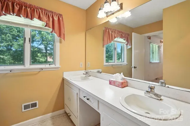 a bathroom with a double vanity sink window and a mirror