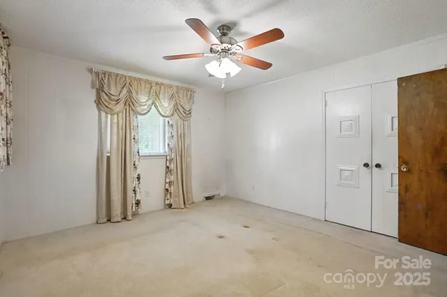 an empty room with windows and fan