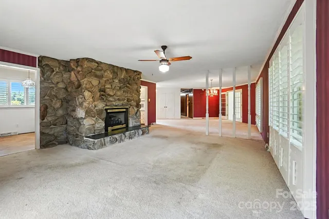 an empty room with windows and fireplace