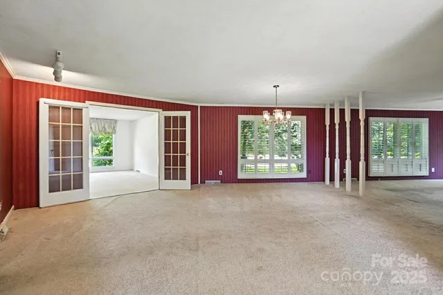 a view of a room with large windows and plants