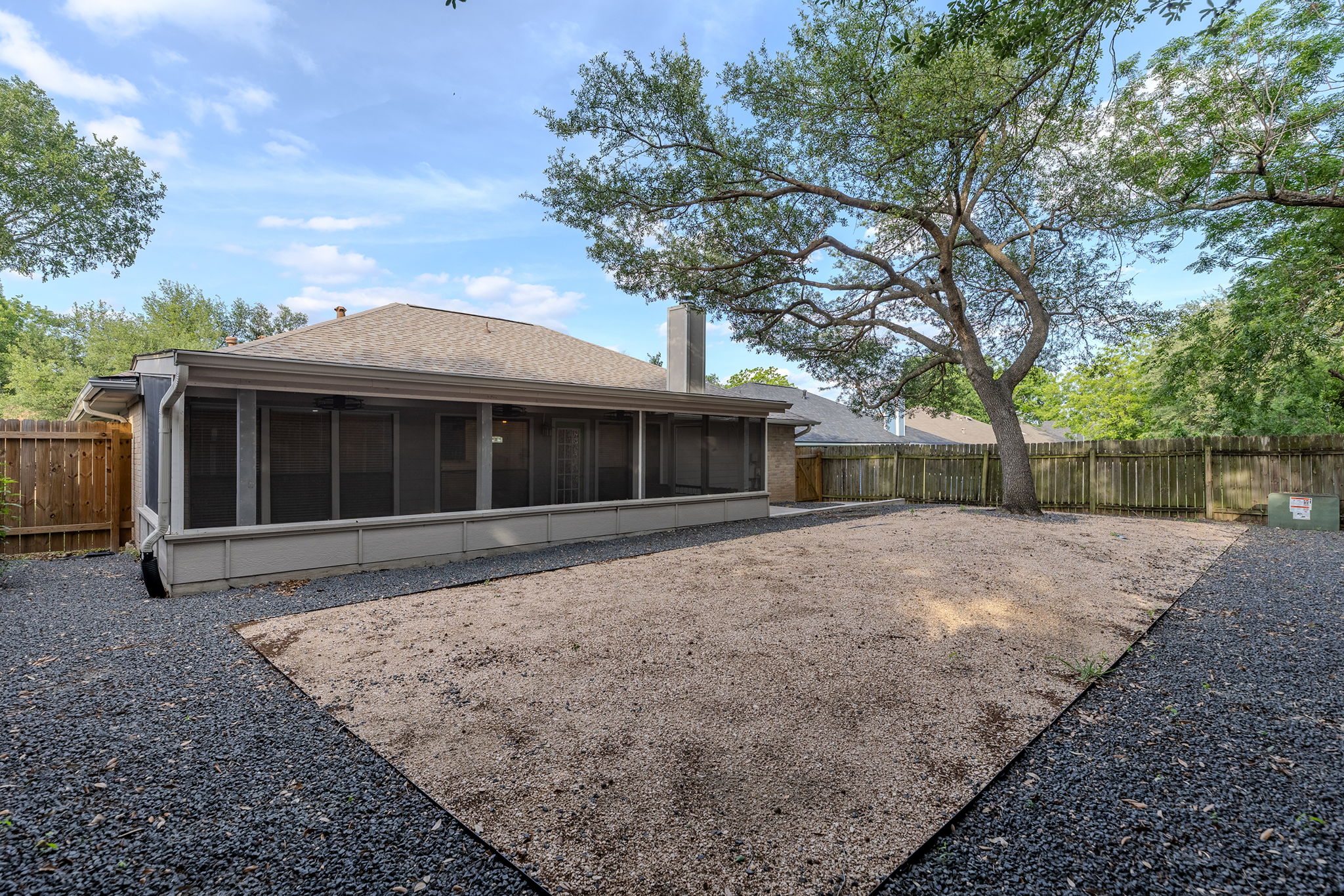 2409 Water Well Lane Austin, TX 78728 - Photo 21 of 22 Backyard featuring a screened-in porch, gravel landscaping, a large mature tree, and wood perimeter fencing