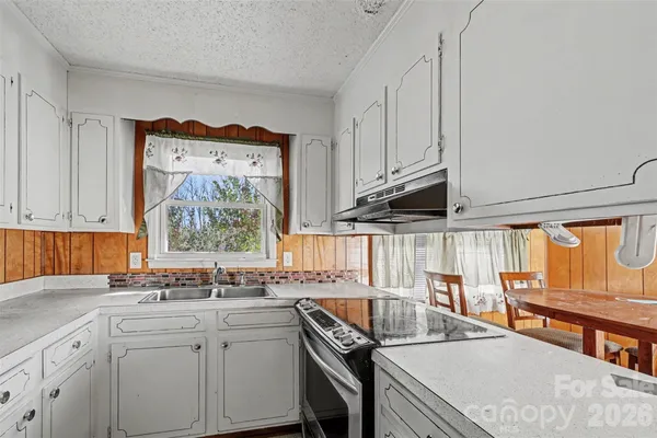 a kitchen with stainless steel appliances granite countertop a sink a stove and a wooden cabinets