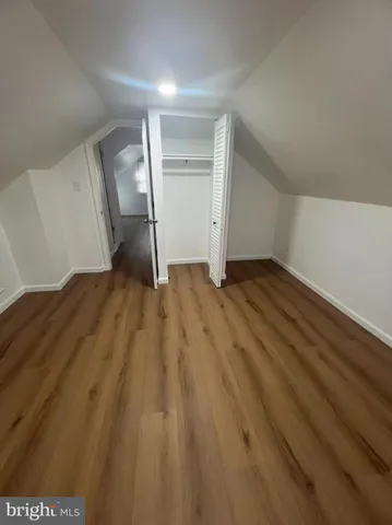 a view of a hallway with wooden floor and a bathroom