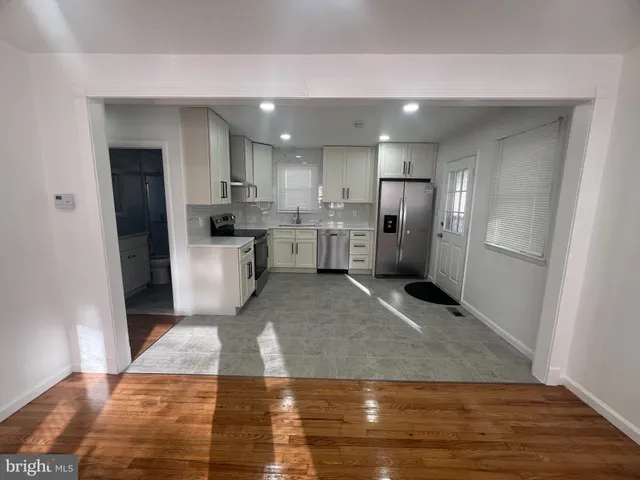 a view of a kitchen with refrigerator and wooden floor