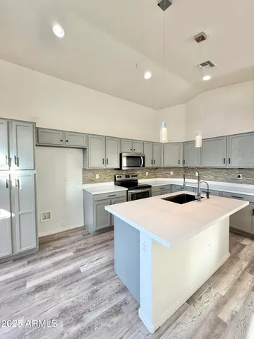 a large kitchen with stainless steel appliances kitchen island a sink dishwasher a refrigerator and a stove with white countertops